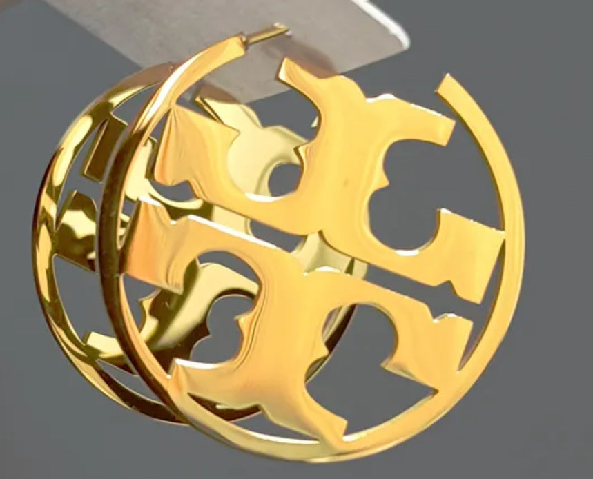Close up side view of elegant 18k Gold plated stainless steel, Tory Burch designer inspired hoop earrings with a smooth, polished finish, designed with a lightweight and tarnish resistant material for timeless sophistication.