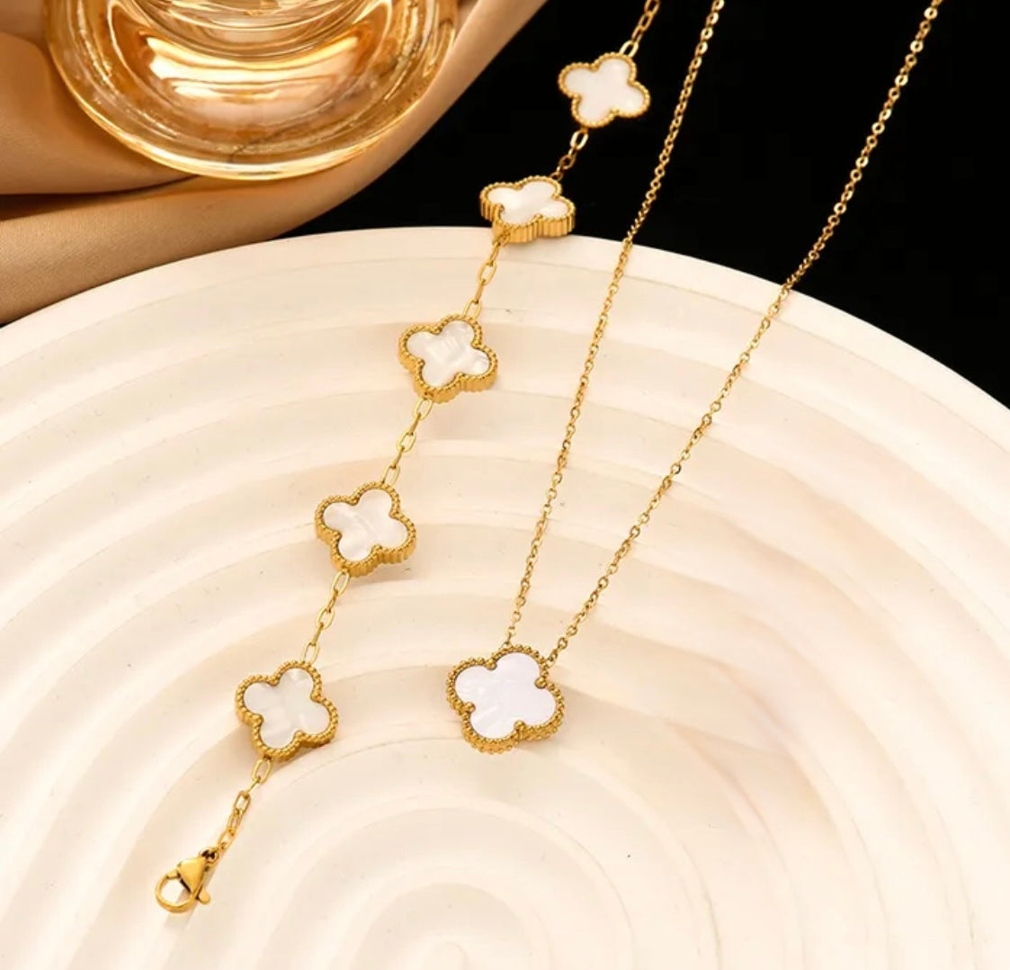 Close up overhead view of elegant 18K gold plated pearl white designer-inspired Van Cleef clover necklace and bracelet set. Lightweight and versatile design, with long lasting, waterproof plating perfect for any occasion, from casual outings to formal events.