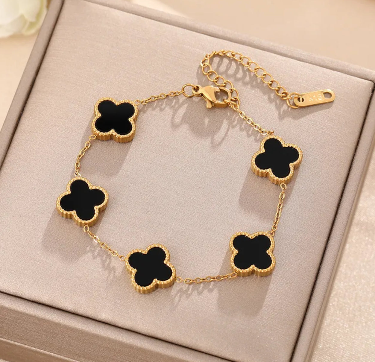 Close up overhead view of elegant 18K gold plated black designer-inspired Van Cleef clover bracelet. Lightweight and versatile design, with long lasting, waterproof plating perfect for any occasion, from casual outings to formal events. 
