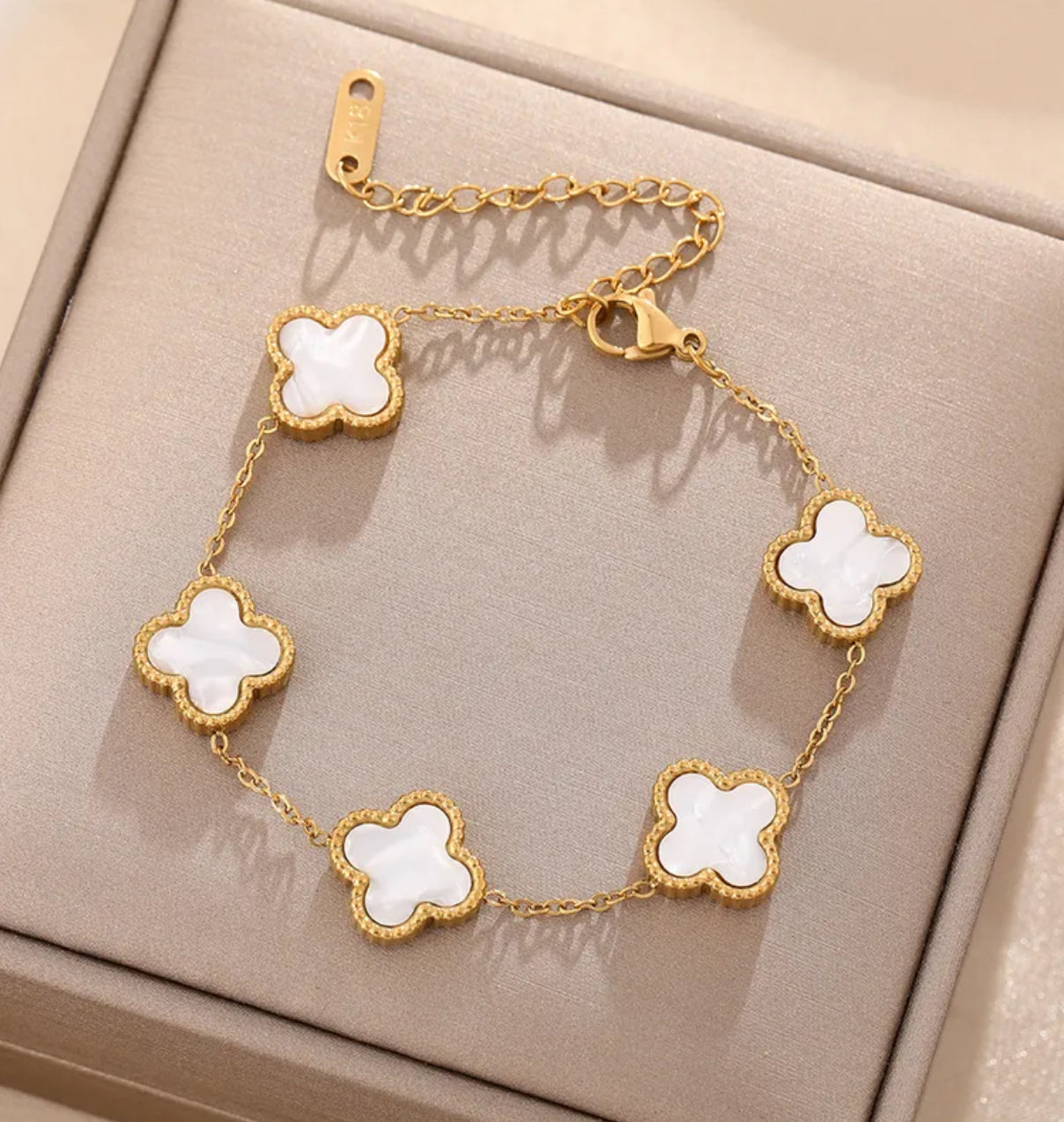Close up overhead view of elegant 18K gold plated pearl white designer-inspired Van Cleef clover bracelet. Lightweight and versatile design, with long lasting, waterproof plating perfect for any occasion, from casual outings to formal events. 